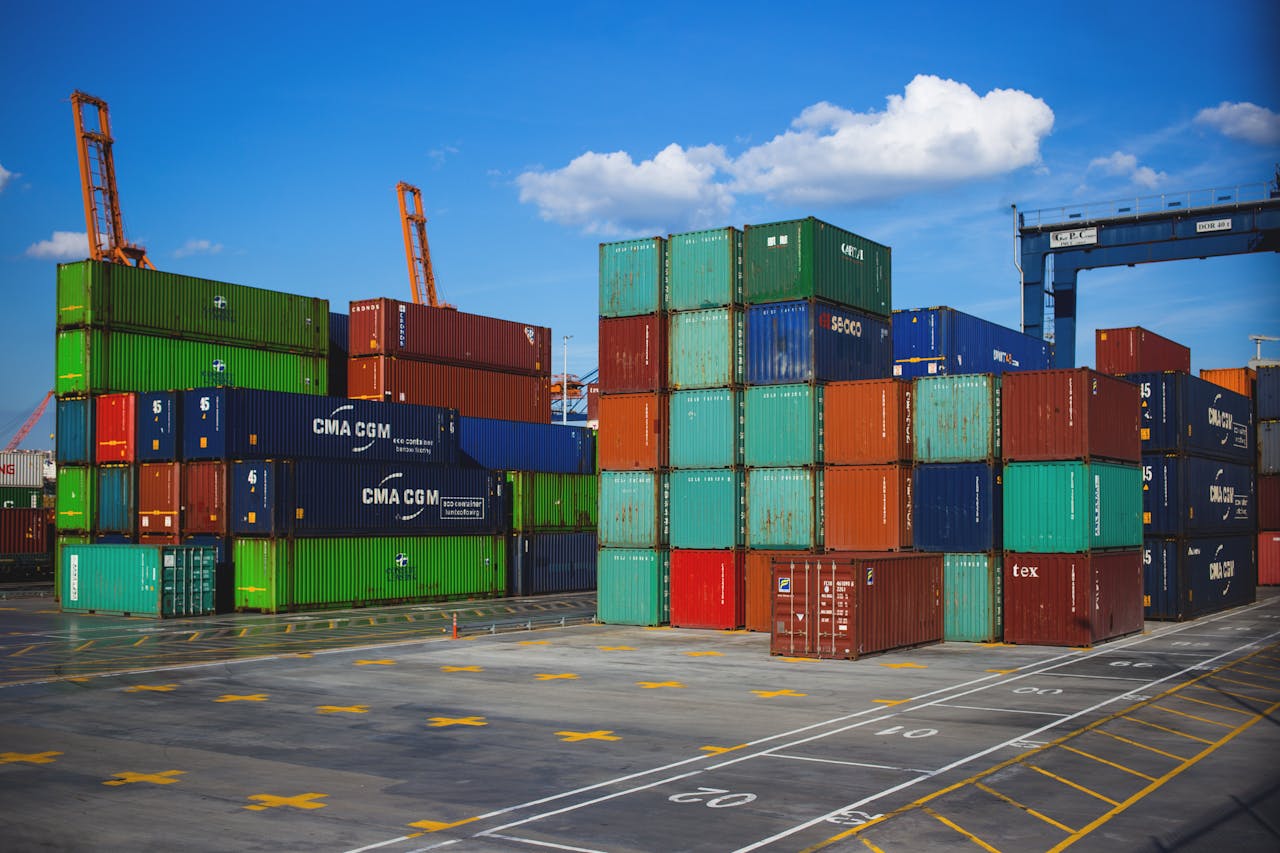Services Vibrant shipping containers stacked at an industrial port under a blue sky.